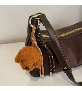Détail d'un sac bandoulière en cuir marron foncé avec un charmant chien en peluche
