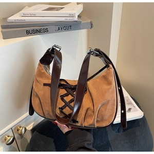 Detail of khaki suede underarm bag featuring leather cross-lacing and glossy shoulder strap