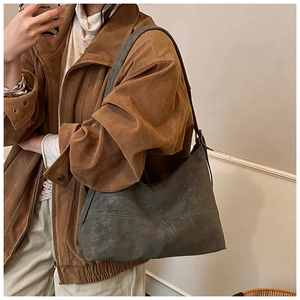 Detail of vintage grey hobo bag with cross stitching and adjustable strap on a model