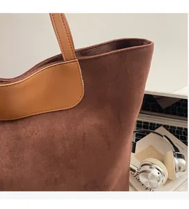 Detail of premium brown suede tote bag showing soft matte texture and smooth leather stitching