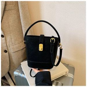 Detail of a chic black leather bucket bag featuring a signature gold buckle and handle