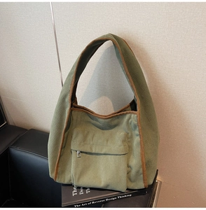 Detail of green corduroy tote bag showing brown piping, metal zipper pocket, and soft texture