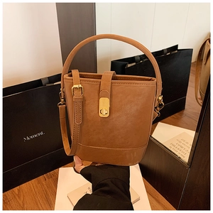 Detailed view of caramel brown bucket bag with golden buckle and textured synthetic leather