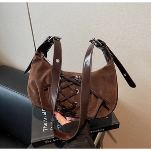 Detail of a brown suede hobo bag featuring decorative lacing and a leather strap with eyelets