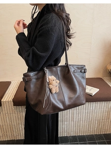 Detailed side view of large brown suede tote bag with decorative bear plush pendant
