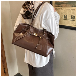 Détail du cabas vintage marron avec surpiqûres contrastées et boucle dorée sur modèle