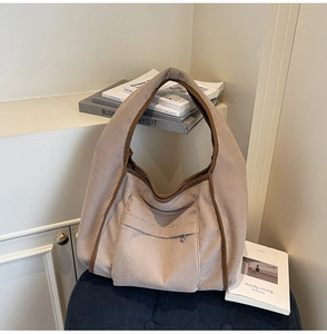 Detailed macro view of beige corduroy tote bag showing ribbed texture and zipper pocket