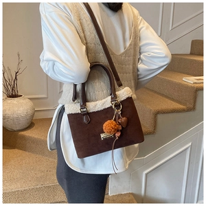 Detail of dark brown matte bucket bag with white faux fur trim and orange pompom charm