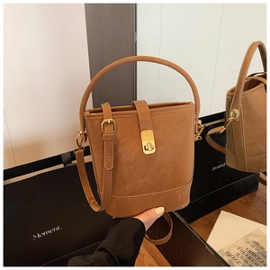 Close-up of brown bucket bag showing textured leather finish and gold turn-lock detail