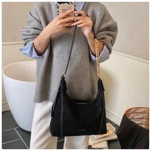 Mirror selfie showing a black matte shoulder bag with white stitching and gold chain strap