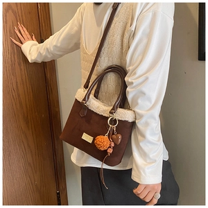 Detail of deep brown suede bucket bag with white faux shearling trim and hanging charms