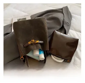 Macro shot of dark brown suede bucket bag interior showing phone and cosmetics