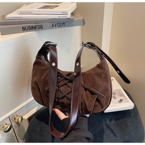 Detail of brown suede hobo bag with leather corset lacing and silver metal eyelets
