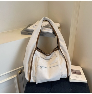 Detail of corduroy tote bag featuring front zipper pocket and brown contrast trim edges