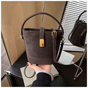 Detailed shot of a dark brown bucket bag with gold vintage buckle and matte leather texture