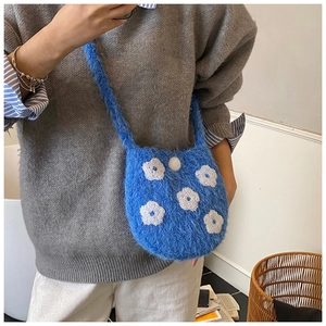 Close-up of blue plush crossbody bag with white flower embroidery for winter outfits