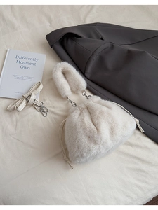 Détail du sac seau en peluche blanche avec cordon de serrage et crochets métalliques