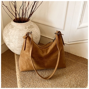 Macro detail of the brown leather tote bag with vertical stitching and textured finish