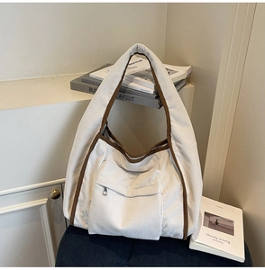 Detail of corduroy tote bag featuring contrast piping and a convenient front zipper pocket
