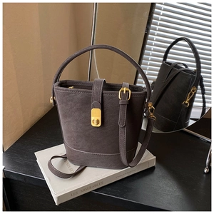 Detailed view of dark brown matte bucket bag with vintage gold clasp and top handle