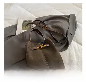 Detail of brown suede bucket bag with gold metal buckle and adjustable shoulder strap