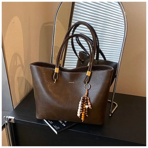 Détail du grand sac cabas en cuir marron foncé avec pendentif perlé et fini élégant