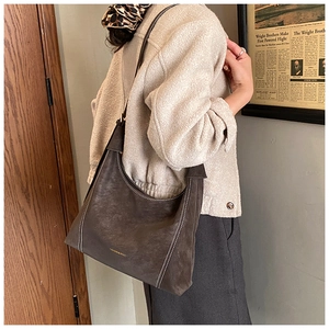 Detail of dark brown suede shoulder bag with contrast white stitching and fashion logo
