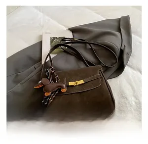 Detail of coffee brown faux suede crossbody bag with metal lock and dog charm