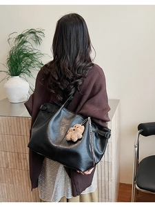 Detailed back view of a black faux suede tote bag with a cute brown bear charm
