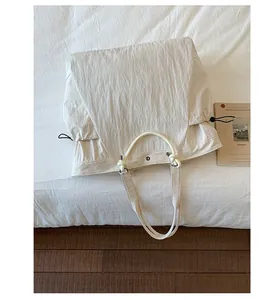 Detail of off-white tote bag showing drawstring closure and textured rope handles