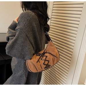 Close-up of hobo bag featuring dark brown leather criss-cross straps and suede texture