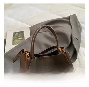 Detail of dark brown leather bucket bag with gold lock and textured patchwork design