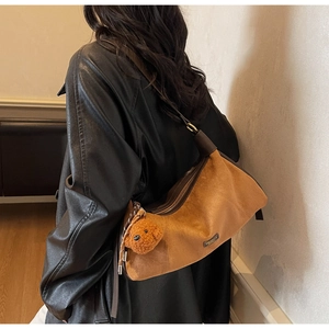 Détail du sac bandoulière en daim marron avec sangle en cuir et breloque ours en peluche