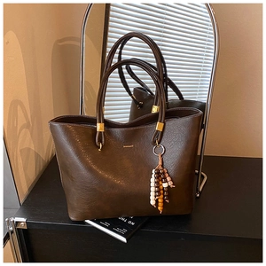 Détail d'un grand sac fourre-tout marron foncé avec grain cuir et breloque en perles