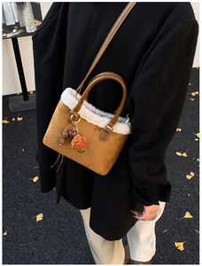 Detail of caramel suede crossbody bucket bag with white faux fur trim and beaded charms
