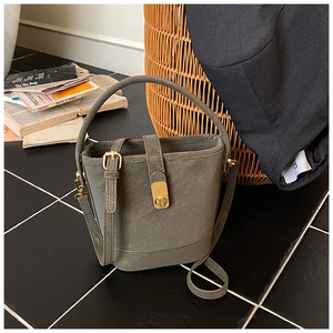 Detailed view of the textured leather texture and gold twist lock on olive green bucket bag