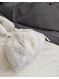 Vue détaillée du sac seau en fausse fourrure crème avec cordon et anneaux métalliques