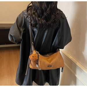 Détail du sac sous le bras en daim marron avec ours en peluche et pompon tissé coloré