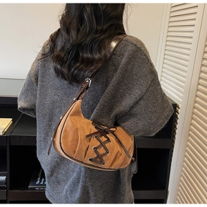 Brown suede underarm bag with bow ribbons and pleated texture shown on model