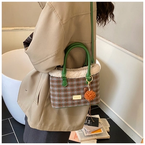 Side view of a knit plaid bucket bag featuring wool trim and a green leather handle