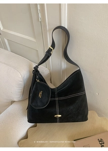 Detail of black suede tote with white stitching, gold buckle, and matching coin purse