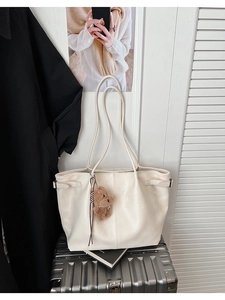 Detail of off-white faux leather tote bag texture with cute plush bear charm decoration
