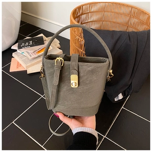 Detailed close-up of olive green bucket bag featuring a vintage gold clasp and fine leather texture