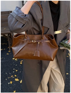 Close-up of vintage brown leather shoulder bag with gold buckle and buckle detail