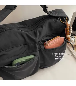 Details einer Nylon-Umhängetasche mit zwei Front-Reißverschlusstaschen für Handy und Geld