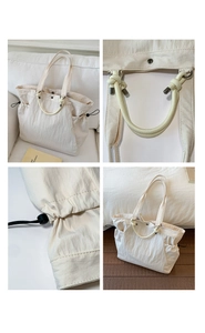 Detail of cream tote bag featuring woven rope handles and a drawstring side closure