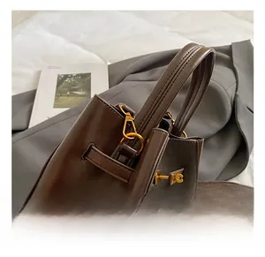 Close-up of premium gold metal hook clasp on smooth dark brown leather bucket bag