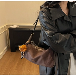 Gros plan du sac bandoulière en daim marron avec un charmant pendentif ours en peluche