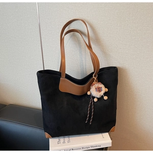 Détail du grand sac cabas en daim noir avec anses en cuir marron et breloque lion