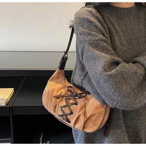 Close-up of suede shoulder bag with brown leather ribbon ties and bow detail
